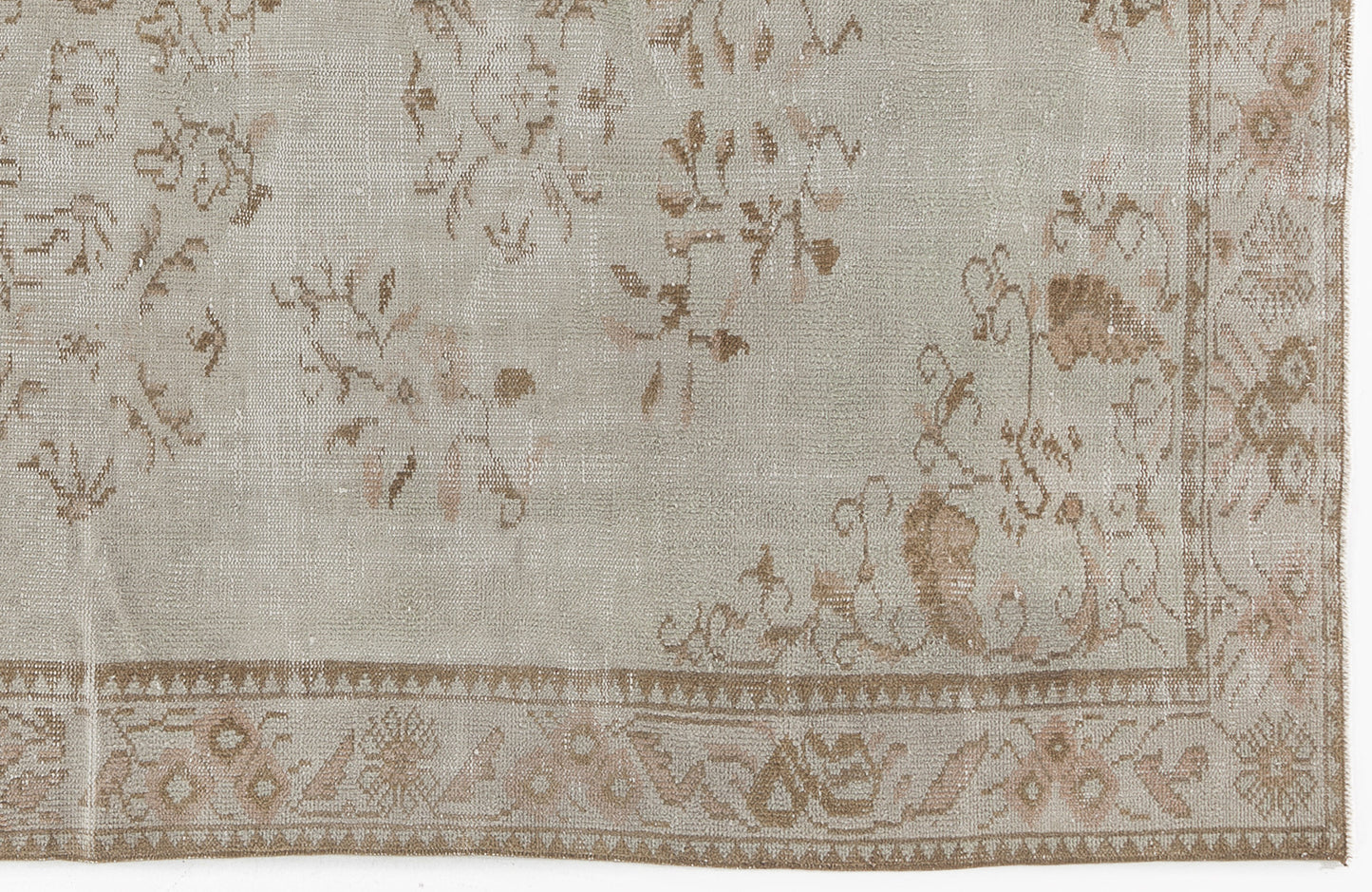 Light gray and beige distressed rug with a faded floral pattern and a detailed geometric border.