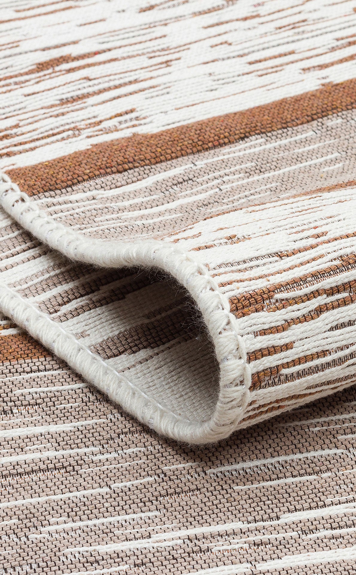 A close-up of the Calm Thread - Washable Double-Sided Kilims - AR27, folded at the edge and displaying a textured pattern in beige, brown, and white stripes—ideal as a neutral area rug for any room.