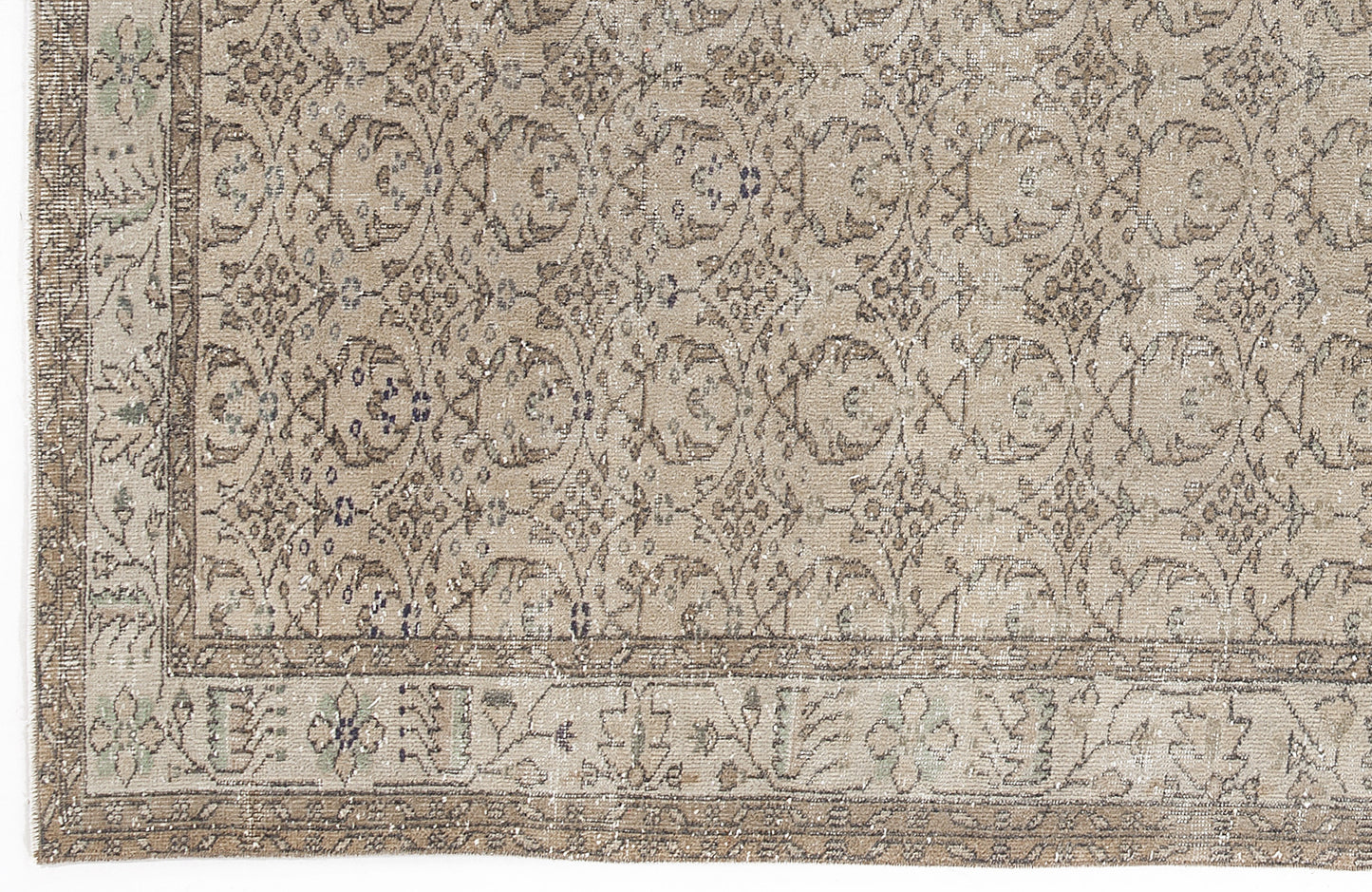 Beige and taupe distressed rug with a repeating floral medallion pattern and a decorative border.