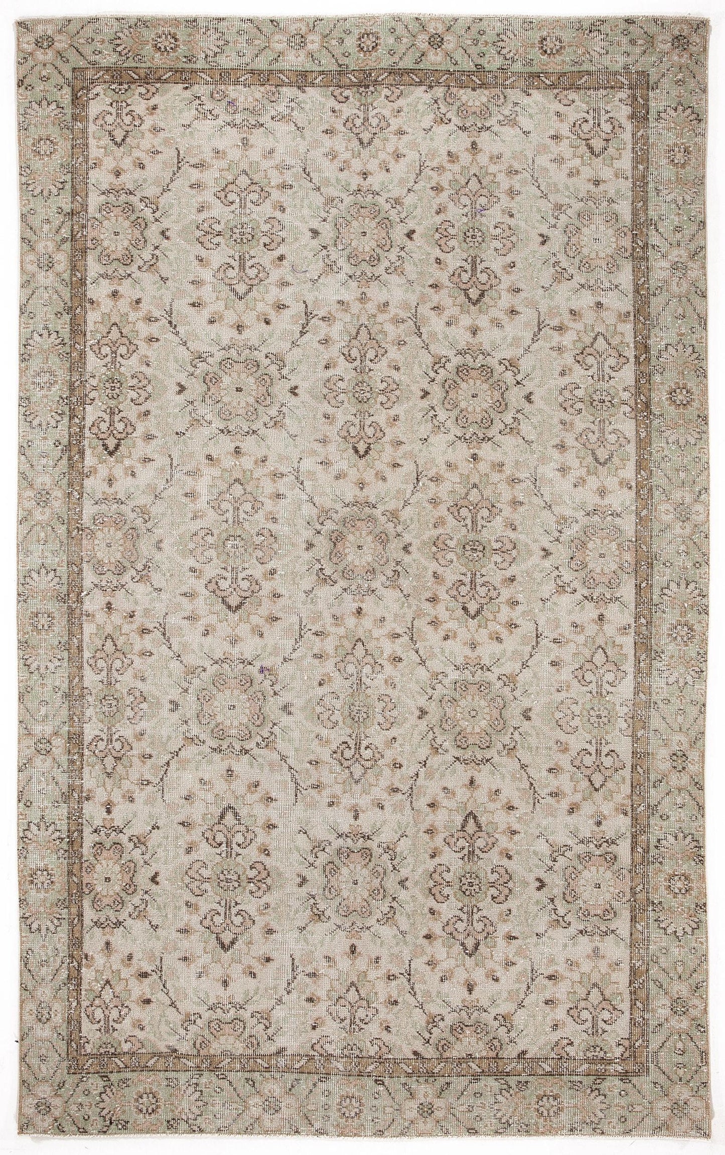 Beige and sage green vintage-style rug with a repeating floral medallion pattern and a decorative border.