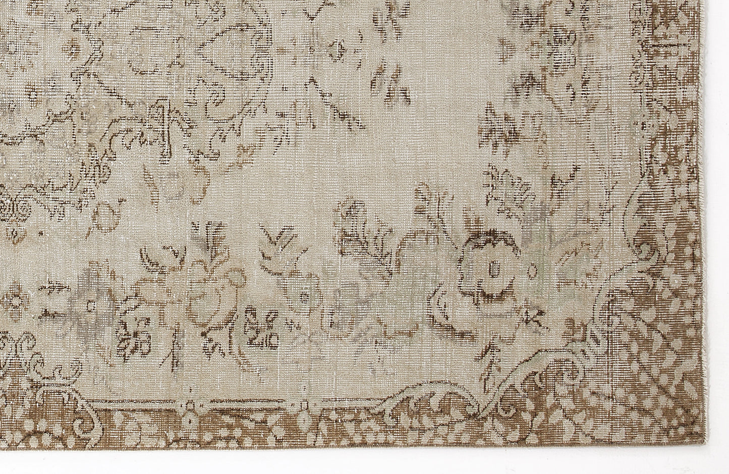 Beige and brown vintage-style rug with a faded floral medallion pattern and a decorative border.