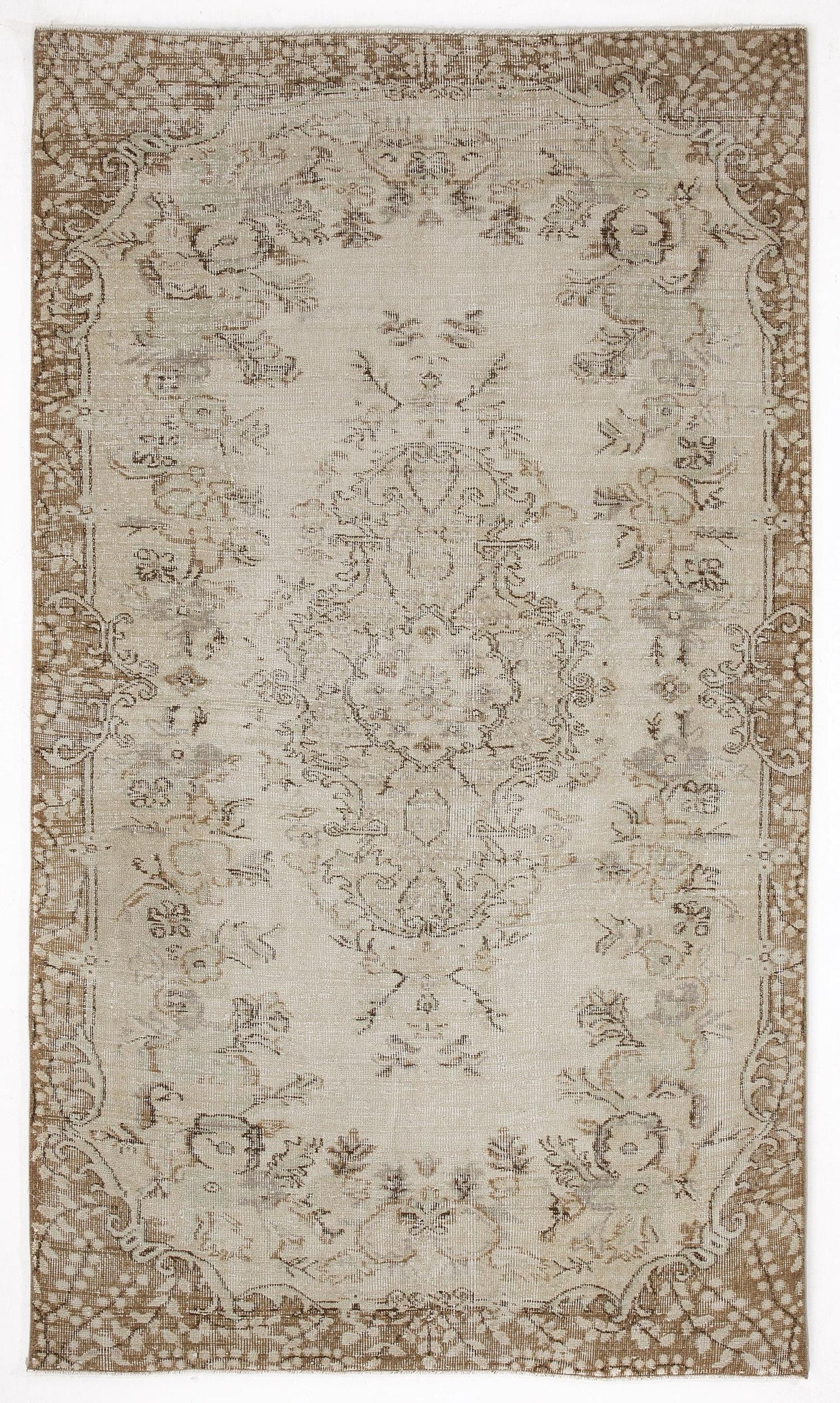 Beige and brown distressed area rug with a central floral medallion and ornate border on a white background.