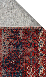 A close-up of the Heritage Blend - Washable Kilims - AND02 rug shows its red and navy chenille polyester pattern and decorative border. The corner is flipped to display a gray, dotted non-slip backing—an allergy-conscious choice.