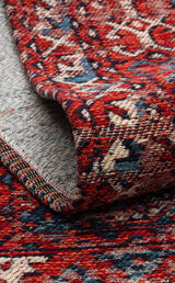 A close-up of the Heritage Blend - Washable Kilims - AND02 shows its red, blue, and cream pattern with a folded corner, highlighting the texture and intricate woven design