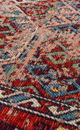 Close-up of Nomad Spirit - Washable Kilims - AND03 reveals its colorful flatwoven texture and intricate patterns in red, blue, green, and beige, highlighting the detailed design of this washable kilim fabric