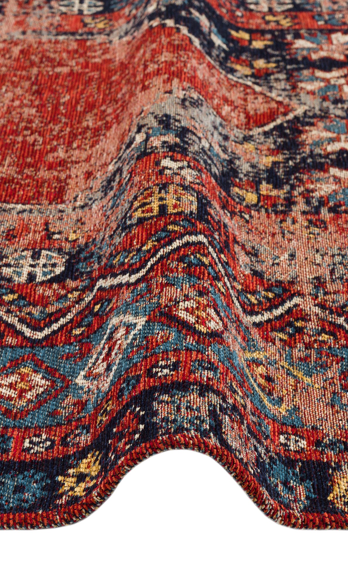 Close-up of the Vintage Echo - Washable Kilims - AND04 chenille-polyester rug, showcasing its red, blue, and yellow vintage-inspired patterns with a wavy fold that highlights the detailed texture