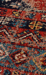 A close-up of the Vintage Echo - Washable Kilims - AND04 rug showcases intricate geometric patterns in red, blue, yellow, and cream with zigzags and symmetrical motifs for a colorful, textured vintage look