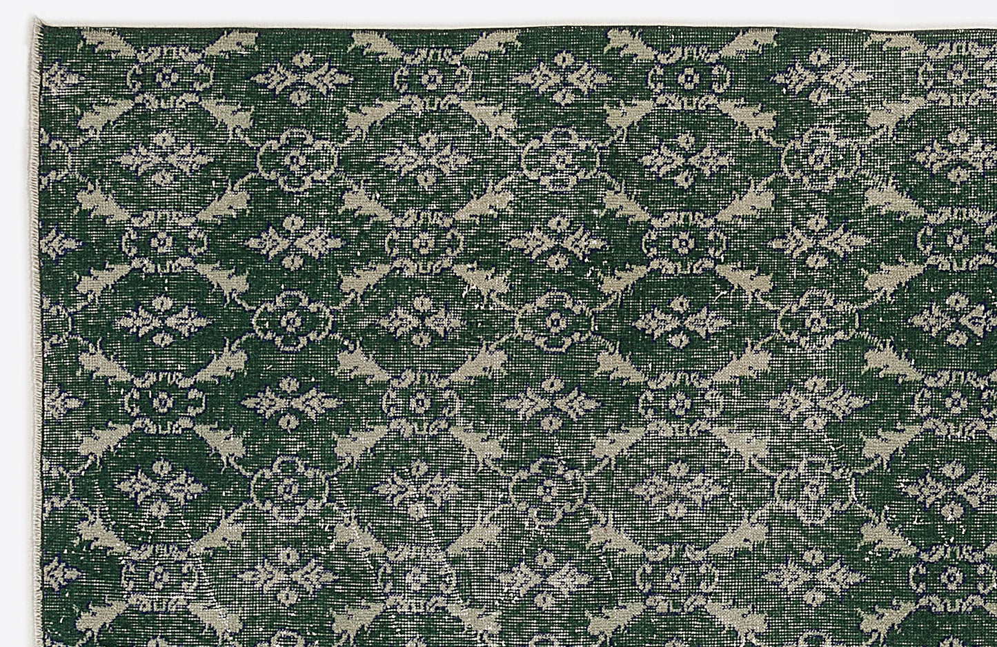 Dark green rug with a repeating light grey floral medallion and lattice pattern.