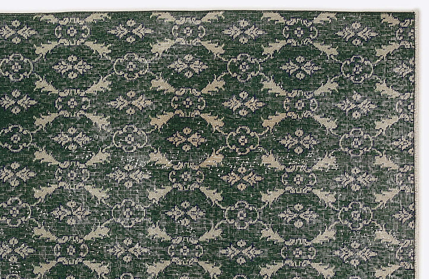 Dark green rug with a repeating beige floral medallion pattern and distressed texture on a white background.