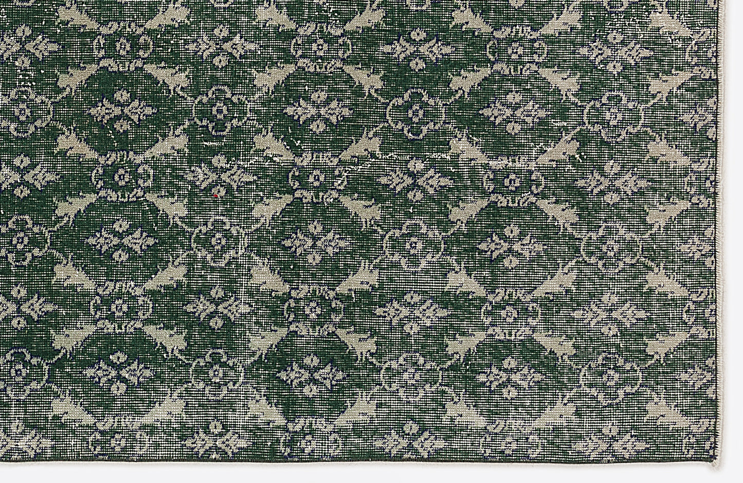 Dark green rug with a repeating cream-colored floral medallion and lattice pattern.