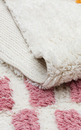A close-up of the Nursery Nest - Washable Shaggy - CBN04 rug shows its plush, textured underside, with a pink geometric pattern on a soft white background—perfect for nursery decor.