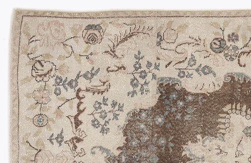 Load image 1 in gallery view. Beige vintage-style rug with a distressed floral pattern in muted brown, blue, and pink tones.