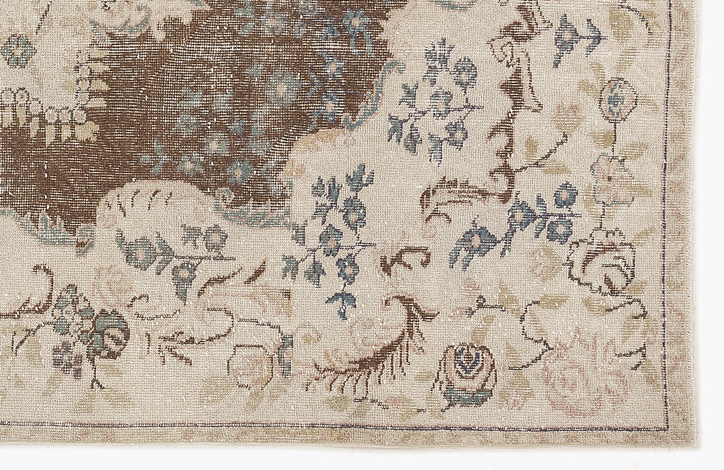 Beige and brown traditional rug with a distressed floral pattern and muted blue accents.