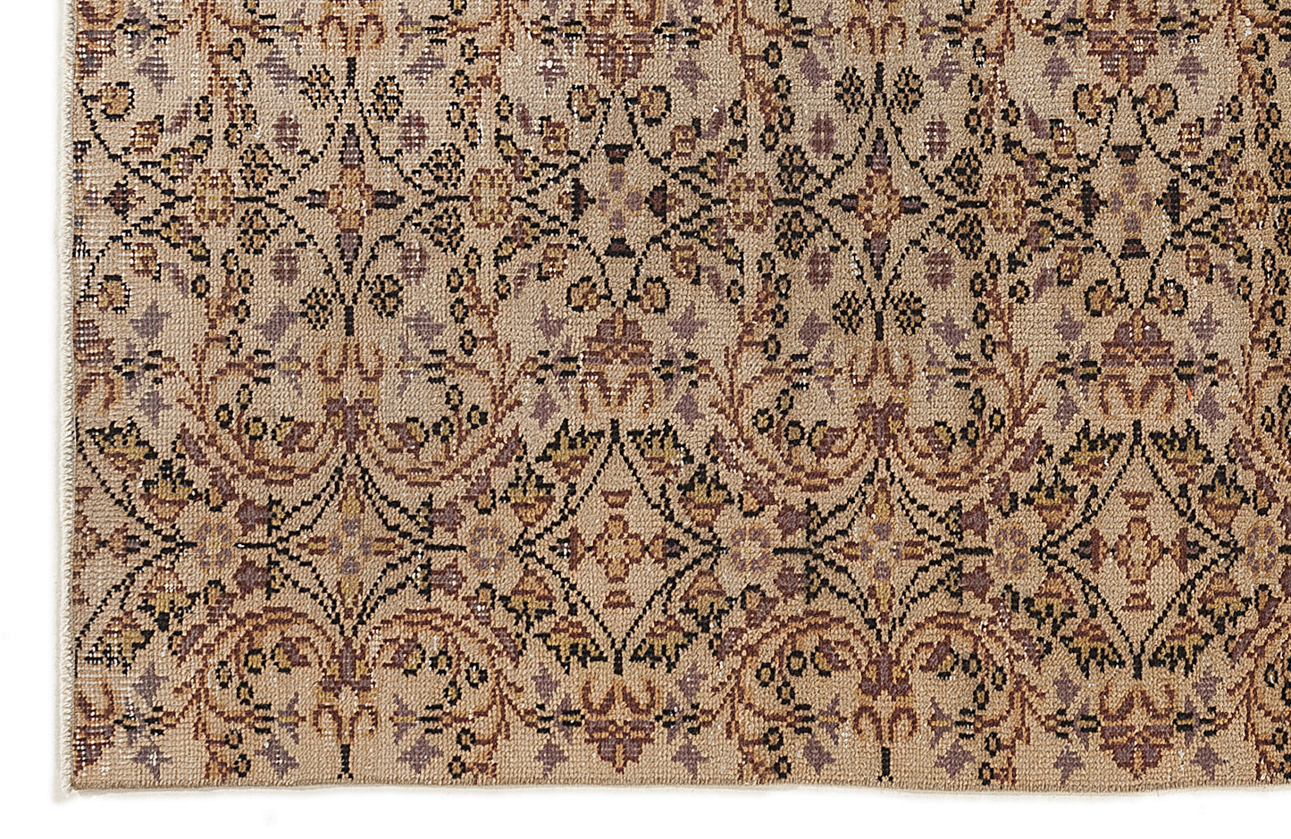 Beige rug with a repeating black, brown, and muted purple floral medallion pattern in a distressed, vintage style.