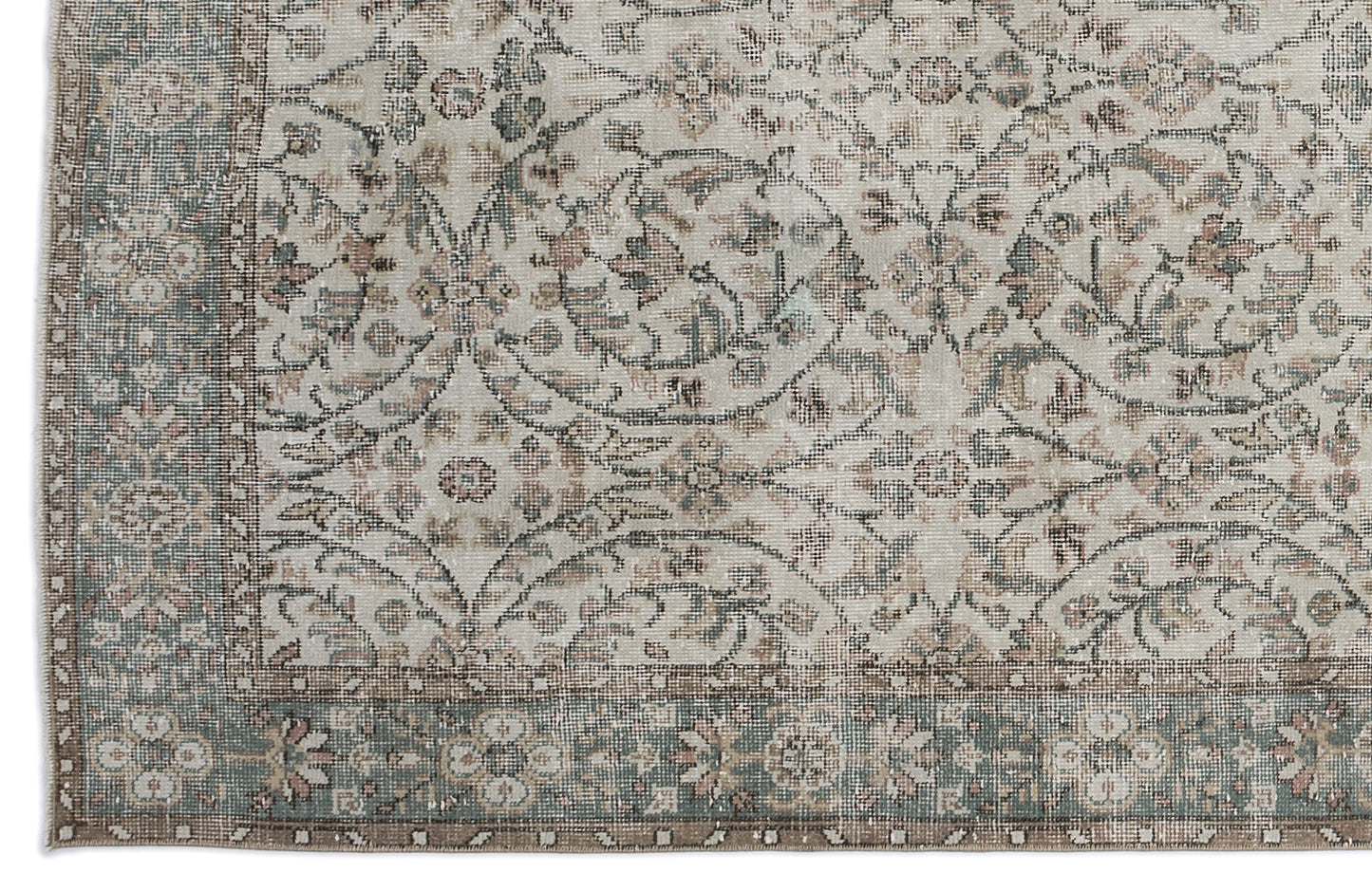 Distressed beige rug with a faded floral medallion pattern in muted sage green and dusty rose, featuring a wide border.