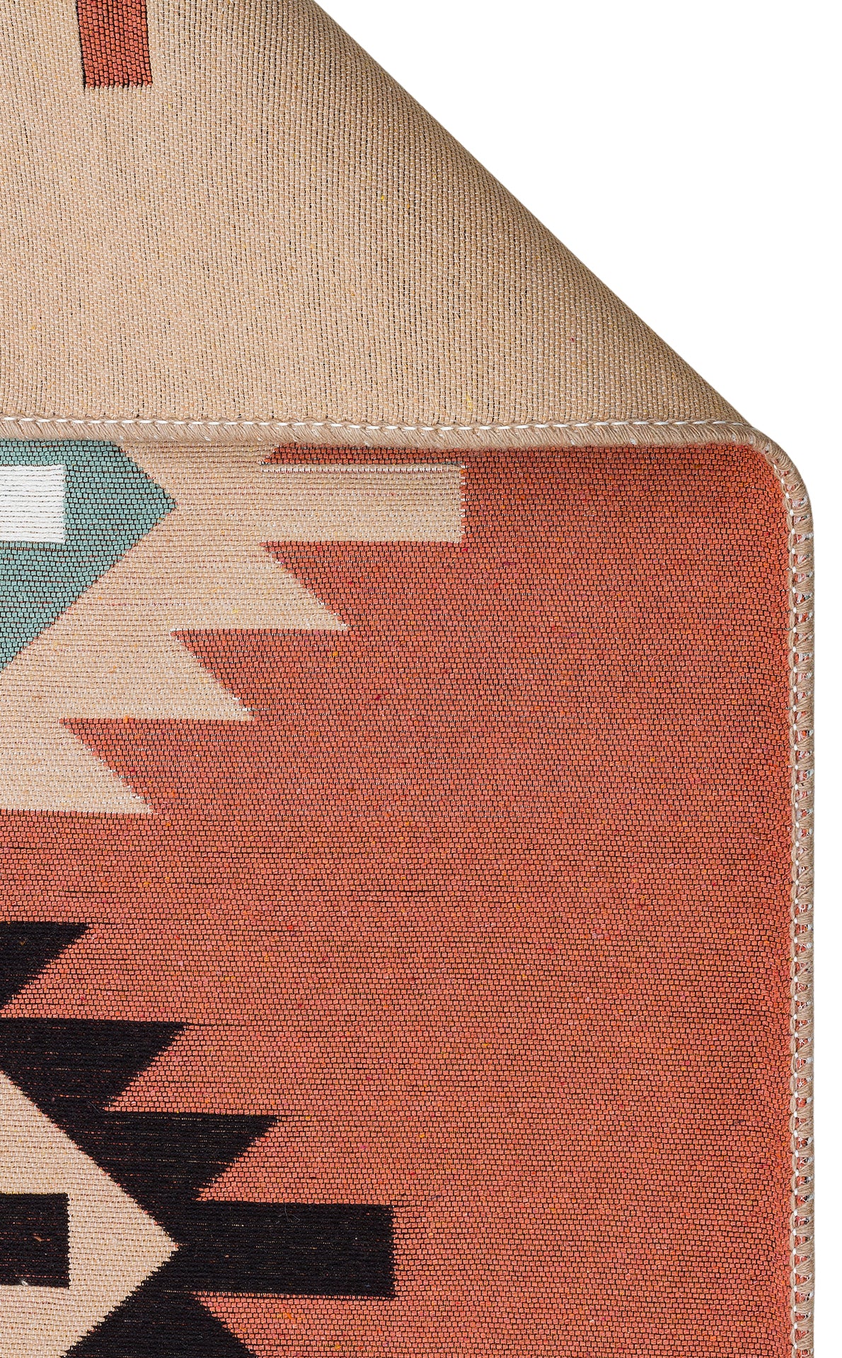 A close-up of the Artisan Mesh - Washable Double-Sided Kilims - AR39 shows its multicolour geometric patterns in red, black, white, and green. One corner is folded over to reveal the solid beige underside and stitched edge. Made from recycled cotton.