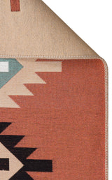 A close-up of the Artisan Mesh - Washable Double-Sided Kilims - AR39 shows its multicolour geometric patterns in red, black, white, and green. One corner is folded over to reveal the solid beige underside and stitched edge. Made from recycled cotton.