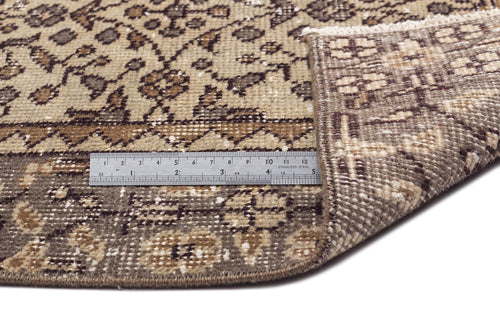 Load image 1 in gallery view. Brown and beige traditional patterned rug with a folded corner and a metal ruler for scale on a white background.