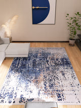 A modern living room with a light gray sectional sofa, the Abstract Atmosphere - Washable Rug - JR834 (Custom Size) in blue and white for high-traffic areas, potted plants, and matching geometric wall art above a wooden floor.