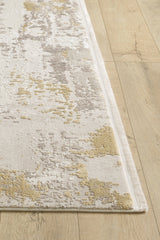 A close-up of the Abstract Blitz Premium Rug - Gold - M658F showcases its textured abstract pattern in beige, gray, and yellow tones on a light wood floor.