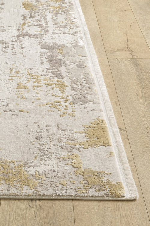 Load image 1 in gallery view. A close-up of the Abstract Blitz Premium Rug - Gold - M658F showcases its textured abstract pattern in beige, gray, and yellow tones on a light wood floor.