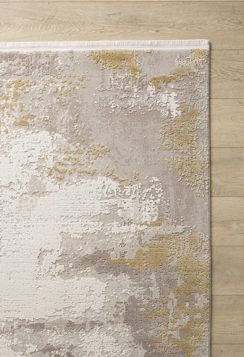 Load image 1 in gallery view. The Abstract Blitz Premium Rug - Gold - M658F features a machine-made abstract design in beige, ivory, gray, and gold with irregular textured patches, bringing contemporary style to a light wooden floor.