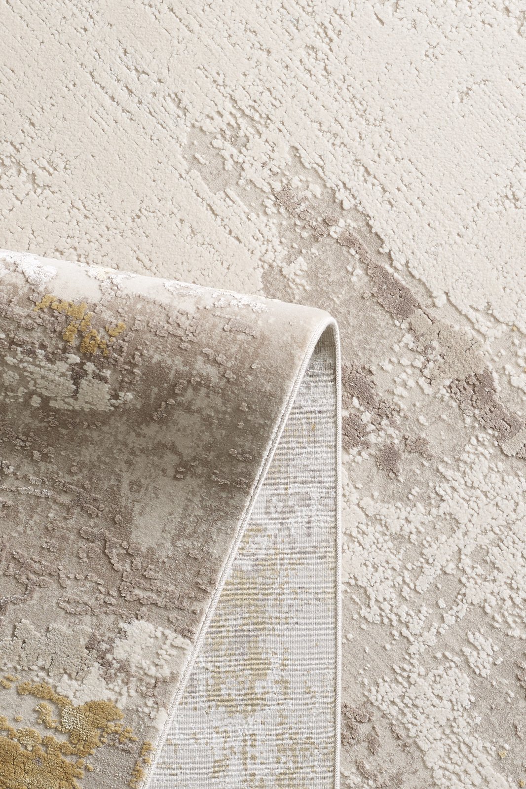 A close-up of the Abstract Blitz Premium Rug - Gold - M658F showcases its textured, modern abstract design in neutral tones with gold accents, with one corner folded to reveal the underside.