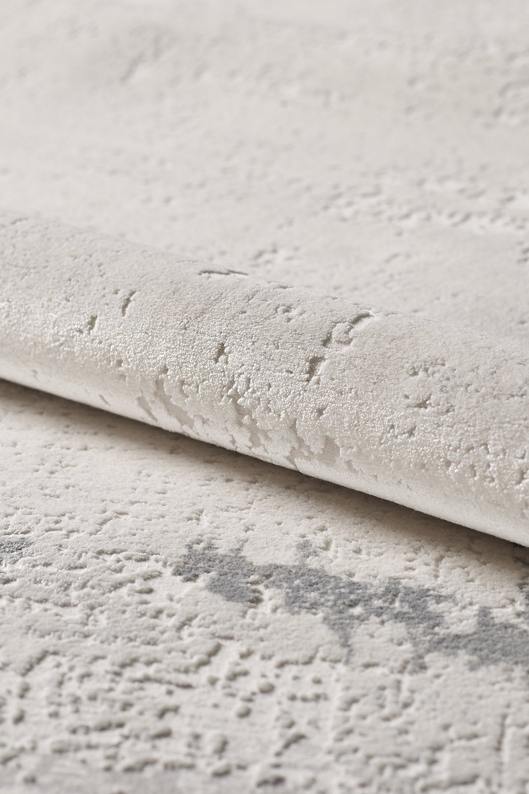 A close-up of the Abstract Blitz Premium Rug - Silver (M658D) shows its light, textured surface with a raised, irregular pattern and subtle shade variations that enhance its soft, plush feel.