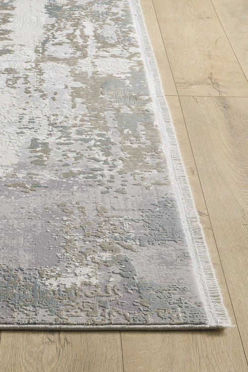 Load image 1 in gallery view. A close-up of the Abstract Blitz Premium Rug - Silver - M658D shows its modern abstract pattern in gray, cream, and light blue on a light wood floor. This machine-made rug features a thin fringe along the edge for added detail.