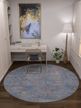 A modern home office features a white desk, chair, tall floor lamp, potted plant, abstract art, and the Abstract Harmony - Machine-Washable Rug JR1882 in blue. Built-in cabinetry surrounds the space for a cozy and tidy feel.