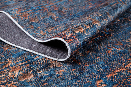Load image 1 in gallery view. A close-up of the Abstract Harmony - Machine-Washable Rug JR1882 (Custom Size), showing its blue and orange pattern with one corner lifted to display the textured gray underside—ideal for high-traffic areas and highlighting its intricate woven detail.