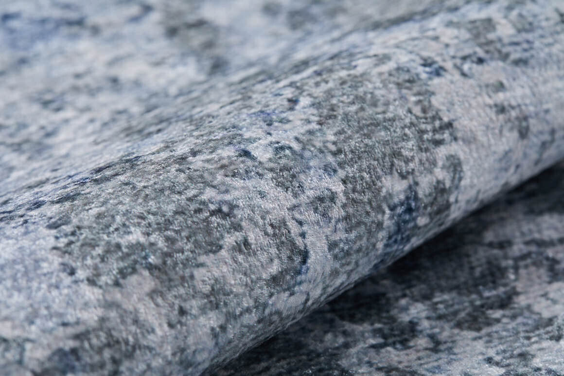 A close-up of the Abstract Oasis - Washable Rug - JR144 (Custom Size) highlights its blue-gray, flat weave design with a textured, mottled surface and soft, raised fibers—ideal for those wanting a stylish, allergy-friendly rug.