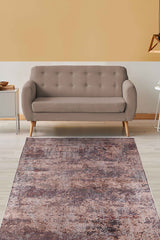 A modern living room with a beige tufted sofa, side table, geometric pendant light, and the Abstract Spectrum - Washable Rug - JR1427 (Custom Size) featuring a distressed brown and pinkish pattern—ideal for high-traffic spaces with light wood floors.