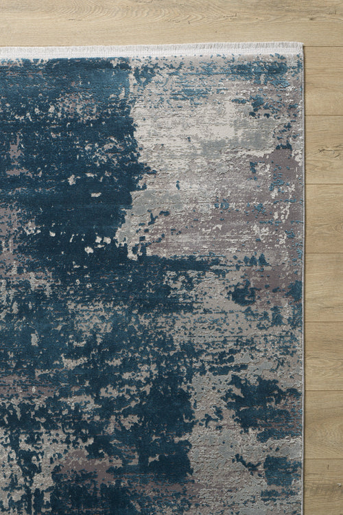 Load image 1 in gallery view. The Abstracta Blue Premium Rug - 1004F features a textured, painterly pattern in dark blue, light gray, and taupe tones. This machine-made rug is displayed on a light wooden floor.