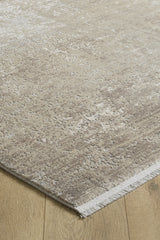 A close-up of the Abstracta Creme Premium Rug - 1004B, featuring a beige and light brown abstract, textured pattern with short fringes, on a light wooden floor. This machine-made rug brings modern elegance to any space.