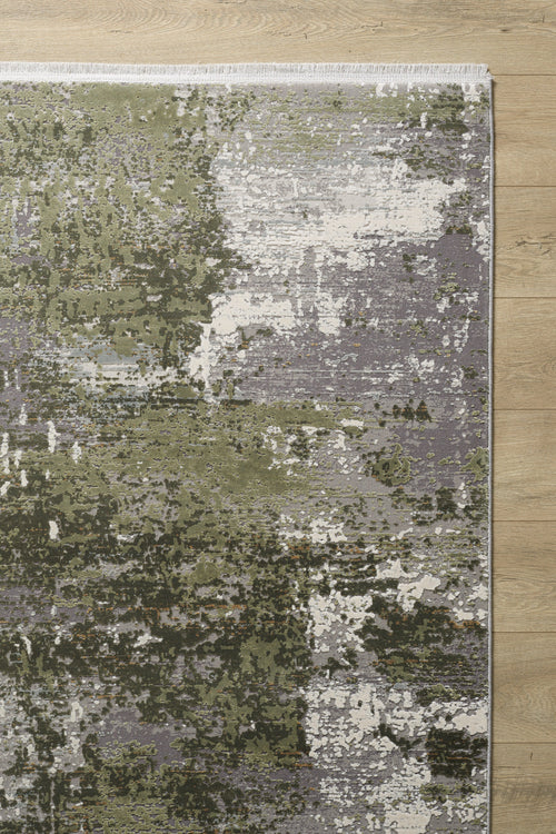 Load image 1 in gallery view. The Abstracta Green Premium Rug - 1004H, featuring an abstract design in green, gray, and white tones, adds a modern textured look to the light wooden floor with its artistic blend of colors.