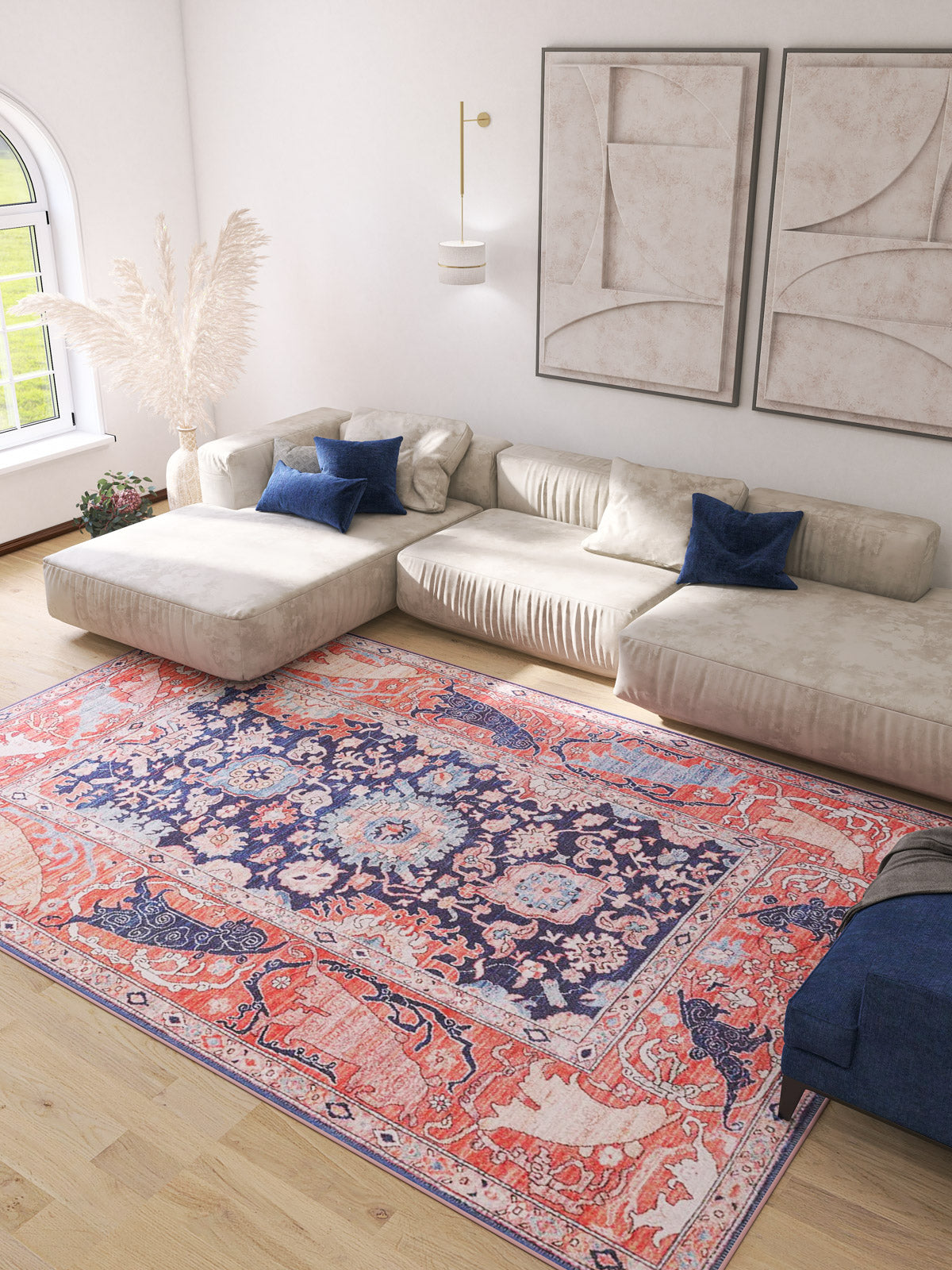 A bright living room features a large cream sectional, blue and cream throw pillows, abstract wall art, sunlit window, and the Aegis Handmade-Design Washable Rug - LCC3029, adding vibrant color atop the light wood floor—ideal for high-traffic areas.