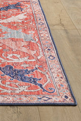A close-up of the Aegis Handmade-Design Washable Rug - LCC3029, featuring pink and blue patterns with a detailed border on a light wood floor. Its vibrant colors and flat weave make it ideal for high-traffic areas.