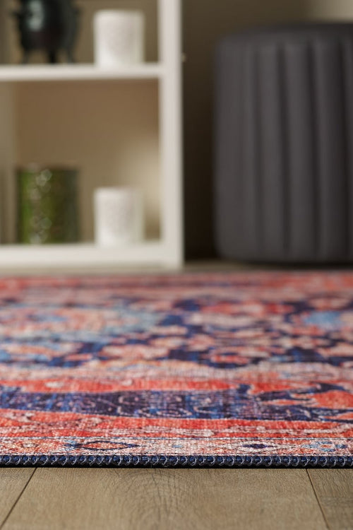 Bild 1 in Galerieansicht laden. A close-up of the Aegis Handmade-Design Washable Rug - LCC3029 on a wooden floor, with shelves and a gray cushioned ottoman blurred in the background—perfect for high-traffic areas.