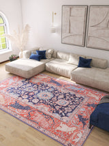 A bright living room with a large beige sectional, blue accent pillows, light wood floors, abstract wall art, and an Aegis Handmade-Design Washable Rug - LCC3029 (Custom Size) ideal for high-traffic areas beside a tall vase of pampas grass near a window.