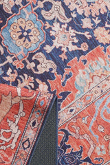 A close-up of the Aegis Handmade-Design Washable Rug - LCC3029 (Custom Size) shows vibrant floral and geometric patterns in red, blue, white, and beige. A folded corner reveals the weave, ideal for high-traffic areas and easy maintenance.