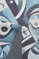 A close-up of the Aesthetic Anomaly Contemporary Washable Rug - MDJ004, showcasing its blue and white abstract geometric face pattern and stitched edge with a folded corner revealing the textured underside—ideal for high-traffic areas.