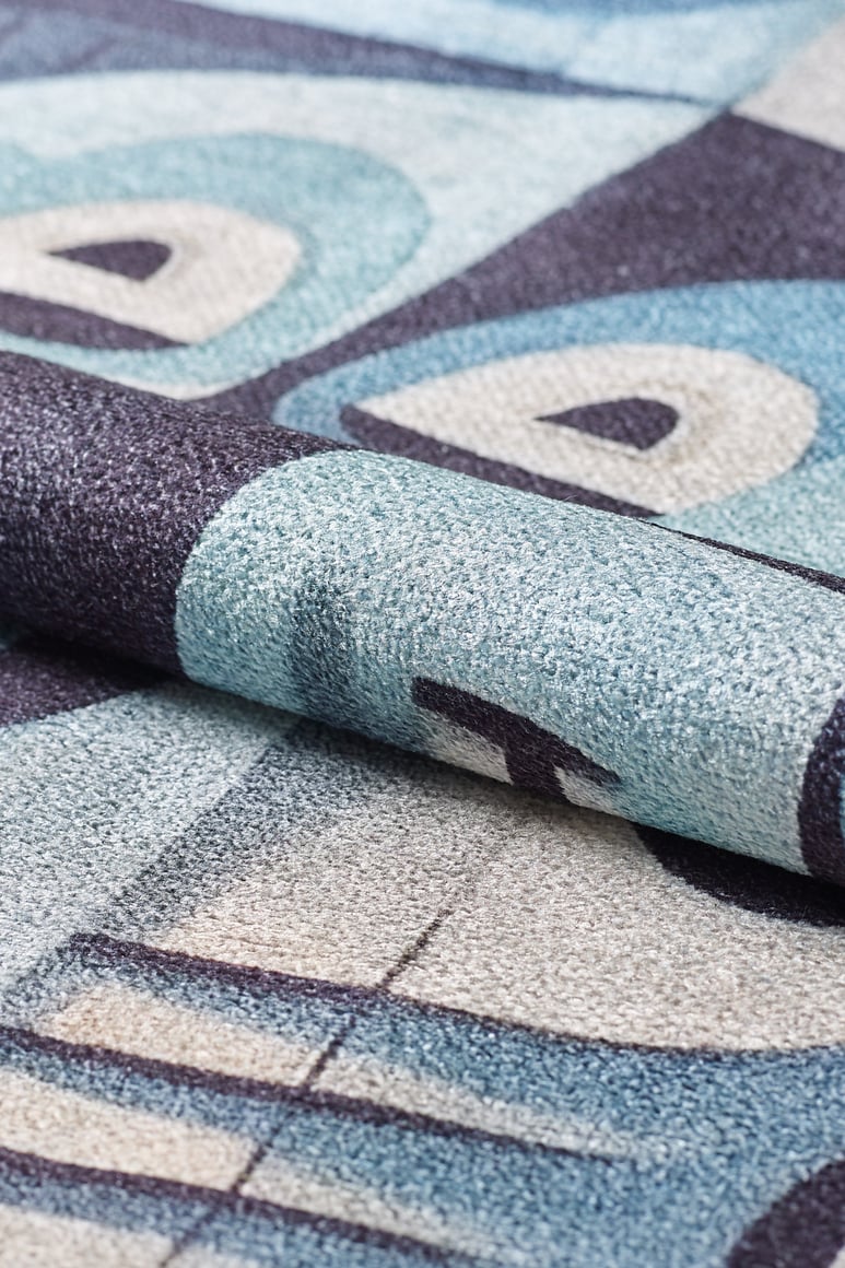 A close-up of the Aesthetic Anomaly Contemporary Washable Rug - MDJ004, featuring a textured surface and abstract geometric pattern in blue, teal, gray, and cream—ideal for high-traffic areas.