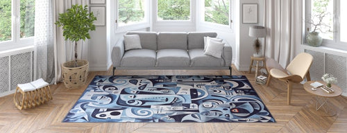 Load image 1 in gallery view. A modern living room with a gray sofa, light wood furniture, large windows, potted plant, and the Aesthetic Anomaly Contemporary Washable Rug - MDJ004 in blue with abstract patterns—ideal for high-traffic areas—on a herringbone wood floor.