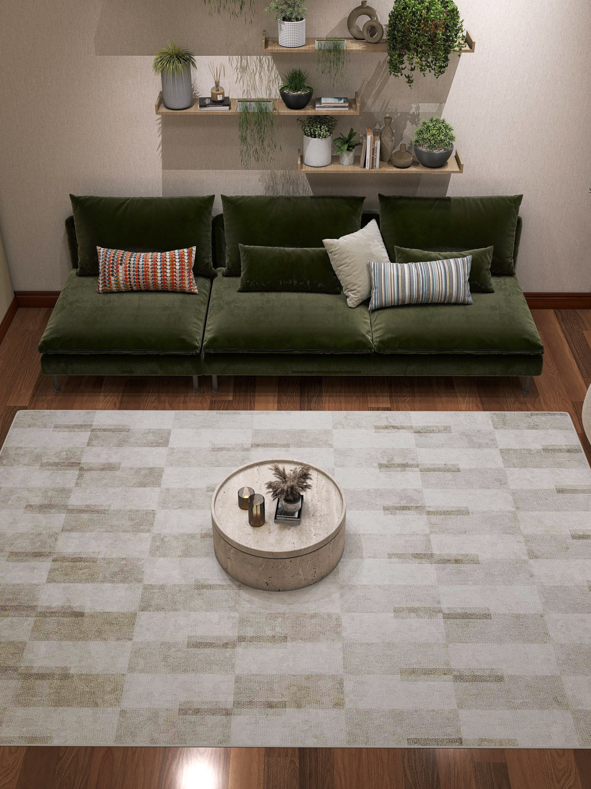 A modern living room featuring a green velvet sofa, assorted pillows, a round coffee table with decor, the Aged Elegance - Washable Rug - JRN37 ideal for high-traffic areas, plus shelves displaying potted plants and books on a beige wall.