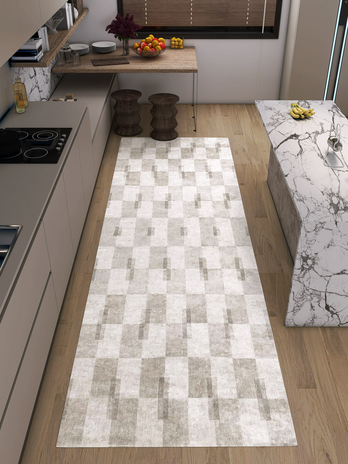 Modern kitchen with light wood floors, marble countertops, and neutral cabinets. The Aged Elegance - Washable Rug - JRN37 with a chevron pattern runs through the space—ideal for high-traffic areas. Fruit bowls and stools are on the counter and table.