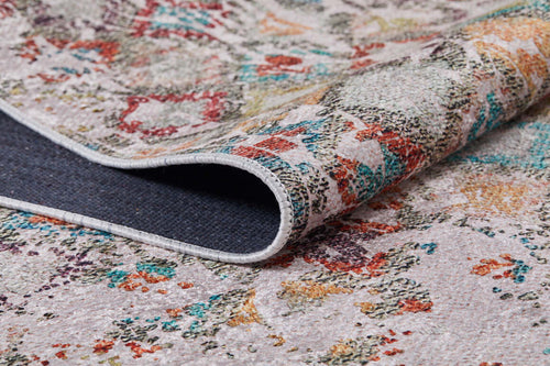 Load image 1 in gallery view. A close-up of the Aged Mosaic - Washable Rug - JR1096 (Custom Size) shows one corner lifted to reveal its dark, textured underside. The rug features abstract red, green, yellow, and blue designs on a light background.