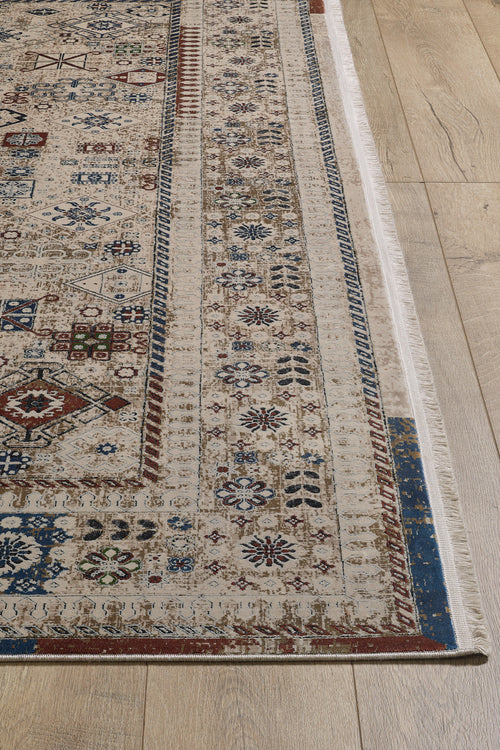 Load image 1 in gallery view. A close-up of the Aged Treasures Premium Rug - 2181A, a machine-made rug with intricate geometric and floral patterns in beige, blue, red, and brown on a light wood floor. Decorative borders accent its edges.