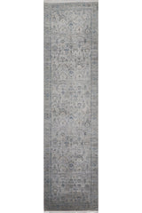 The Ancestral Motifs Turkish Rug - 2225C is a long, rectangular machine-made rug with an intricate floral and medallion design in muted gray, blue, and beige tones. Crafted from modal silk-polyester, it offers a classic, elegant look.