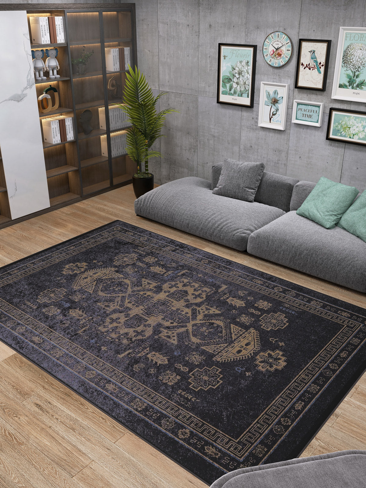 A modern living room with a gray sectional sofa, green cushions, the Ancient Legacy - Washable Rug - JR1890 (ideal for high-traffic areas), a glass-door bookcase, a potted plant, and framed artwork on gray concrete walls above the sofa.